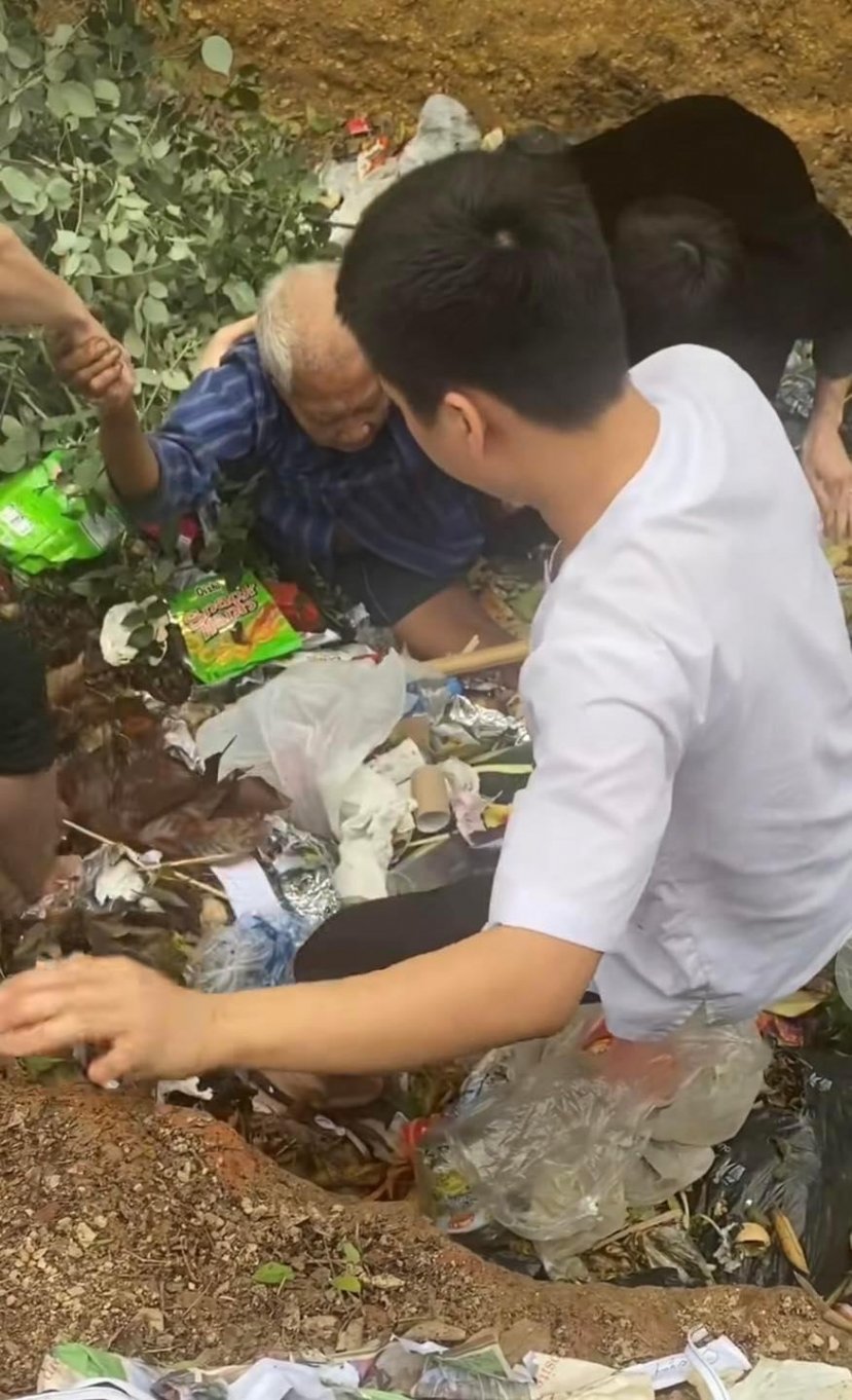 Cụ ông nhặt ve chai rơi xuống hố rác vì mải mê mưu sinh kiếm sống. Ảnh: Nguyễn Đình Phong